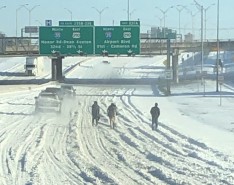 people waling on snowy interstate