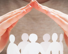 Two hands forming a pyramid over six paper cutouts of people