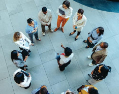A group of people standing in a circle listening to someone standing in the center.