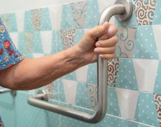 An elderly person holding onto a bath rail.