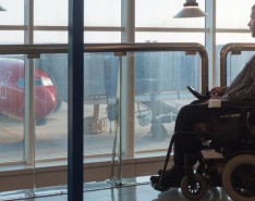 Man in mobility device sitting at airport looking outside at airplanes