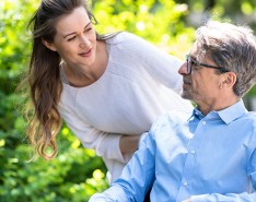 Young white woman smiles at older white man in wheelchair