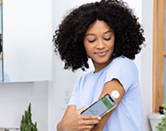 A woman uses her phone to see information from her continuous glucose monitors