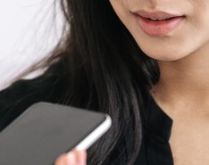 A woman holding a phone up to her mouth, talking to someone on speaker.