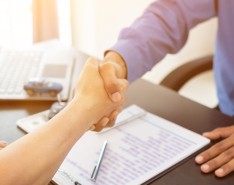 n image of two people shaking hands across a desk. 