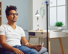 A man sitting on a couch receiving a home infusion therapy