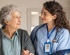 A nurse walking arm in arm with an elderly patient