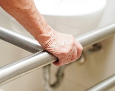 An image of an elderly person holding onto support bars