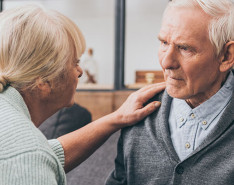Two elderly people talking closely with each other.