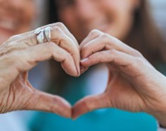 Two people hold their hands together to make the shape of a heart.