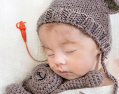 A sleeping infant with a feeding tube in its nose 