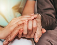 A caregiver and older adult holding hands