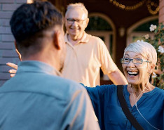 A patient wearing a portable oxygen mask smiling with their arms open to hug someone
