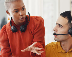 A woman wearing a headset around her neck explaining something to two of her coworkers