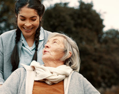 A nurse pushing her elderly patient in a wheelchair.