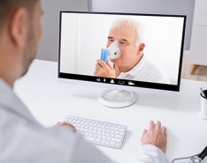 older white man uses nebulizer while on video call