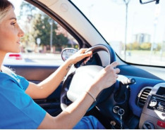 A woman in scrubs driving a car.