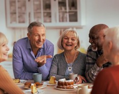 Group of older individuals sitting and laughing while eating cake
