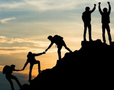 a group of people climbing up a mountain and helping each other reach the top