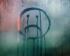 a frown face drawn on a window through condensation