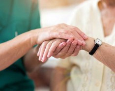 nurse holding older woman's hand