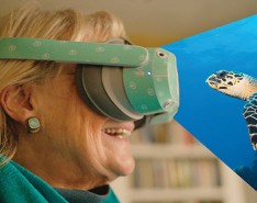 A woman wearing virtual reality smiling at a sea turtle