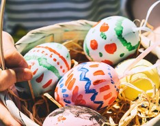 Five colorful Easter eggs in a basket held by a small child