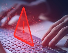 Hands at a keyboard with a large red triangle and exclamation point above it