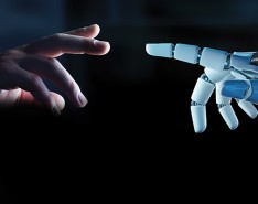 A human hand reaching out to a robot hand on a dark background