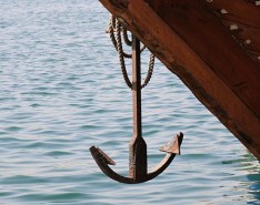 A ship anchor hanging above the water