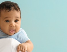 A doctor holds a baby over her shoulder.