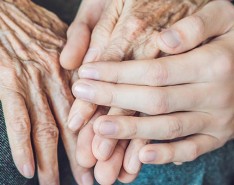 Two elderly hands being held by a younger hand.