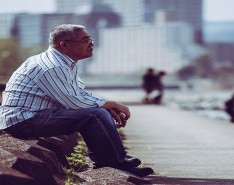 Asian senior adult male sitting alone in a park looking pensive