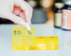 A hand organizing medicine into a pill organizer.