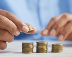 Two hands stacking coins into three columns