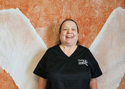 Doris LaPorte standing in front of large angel wings while smiling