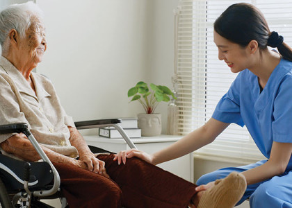 A nurse sits with an elderly patient in a wheelchair.