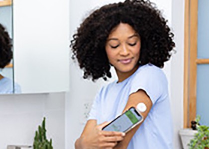 A woman uses her phone to see information from her continuous glucose monitors