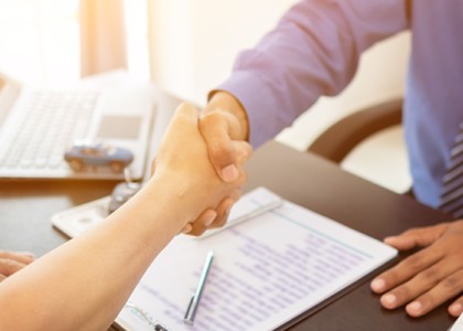 n image of two people shaking hands across a desk. 