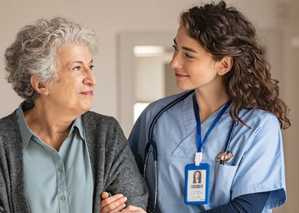 A nurse walking arm in arm with an elderly patient