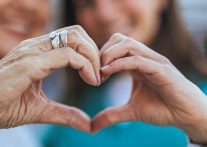 Two people hold their hands together to make the shape of a heart.