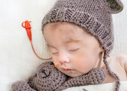 A sleeping infant with a feeding tube in its nose 