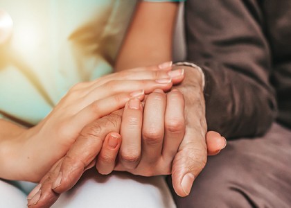 A caregiver and older adult holding hands