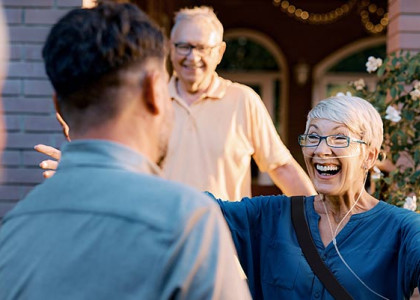A patient wearing a portable oxygen mask smiling with their arms open to hug someone
