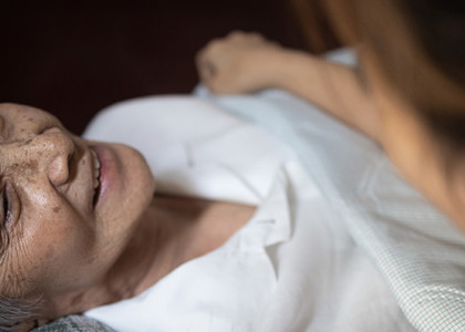 An elderly woman looking up at her caregiver