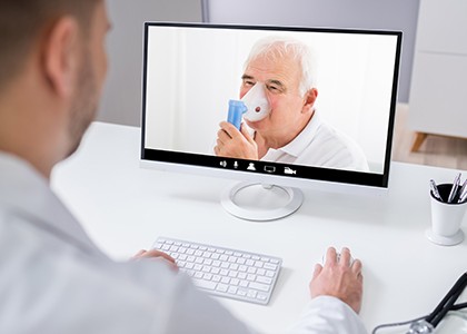 older white man uses nebulizer while on video call