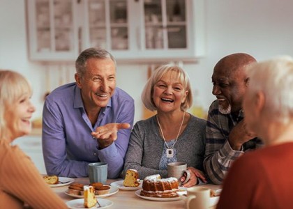 Group of older individuals sitting and laughing while eating cake