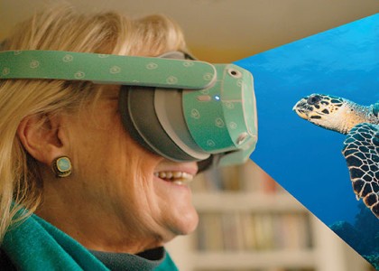 A woman wearing virtual reality smiling at a sea turtle