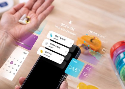 A person holding an iPhone with several screen widgets off to the side as well as a medicine organizer