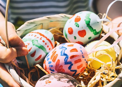 Five colorful Easter eggs in a basket held by a small child